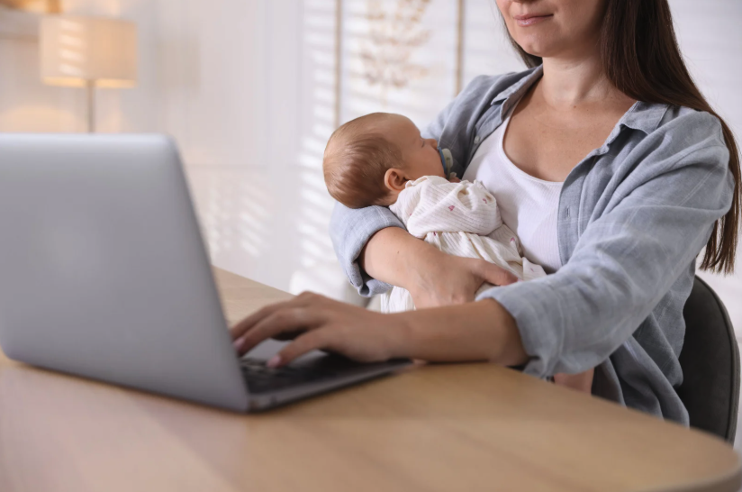 Breastfeeding and Telehealth Support Mother breastfeeding her baby while using a laptop